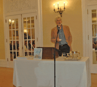 A man stands in front of a microphone and gives a presentation.