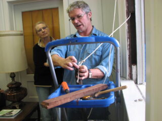 A man holding a sash cord demonstrates how to rehang window weights.
