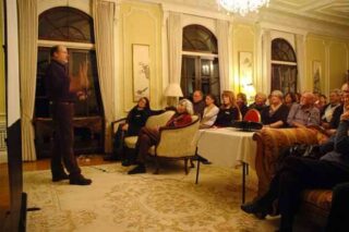 A man presents in front of an audience inside a heritage building.