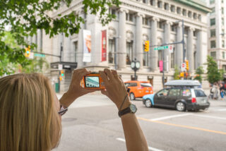 A person is taking a photo of a building's architecture using a digital camera.